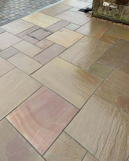 Natural Rippon Buff Indian sandstone paving slabs laid in a landscaped garden UK