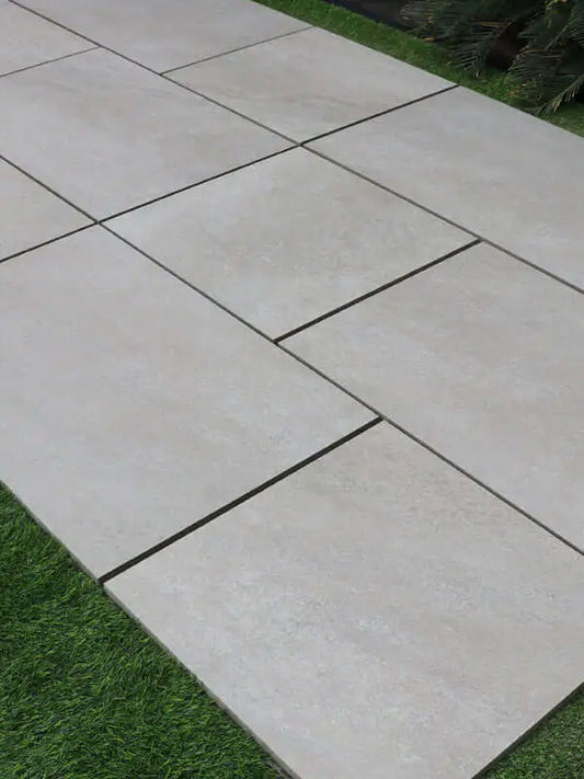High-spec light grey porcelain patio slabs on an outdoor terrace border